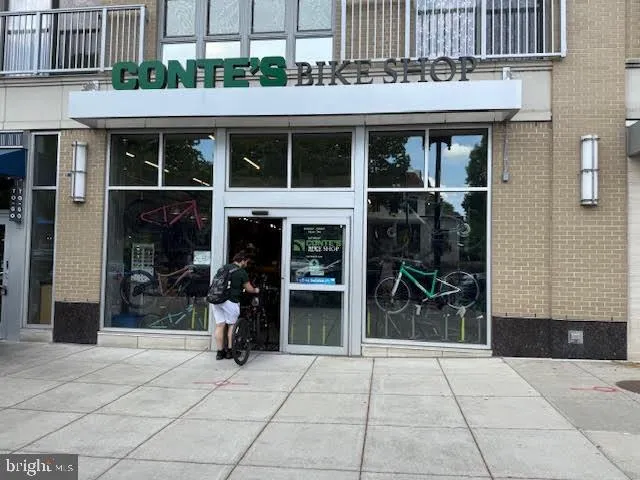 a front view of a building with lots of potted plants and a bench