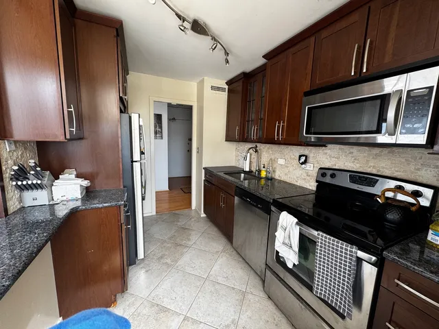 a kitchen with stainless steel appliances wooden cabinets a stove top oven a sink and dishwasher