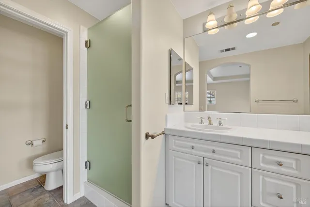 a bathroom with a toilet a sink a mirror and a shower