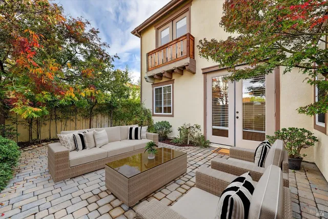 a view of a patio with couches table and chairs with wooden fence and plants