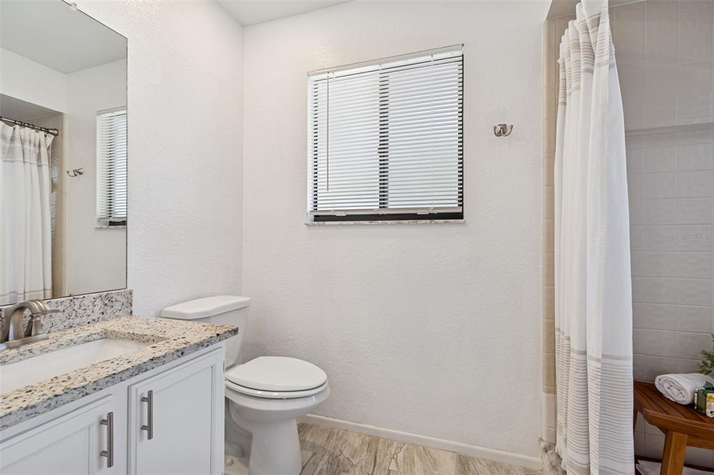 14301 86th Avenue North Seminole, FL 33776 - Photo 20 of 59 a bathroom with a granite countertop sink toilet and a mirror