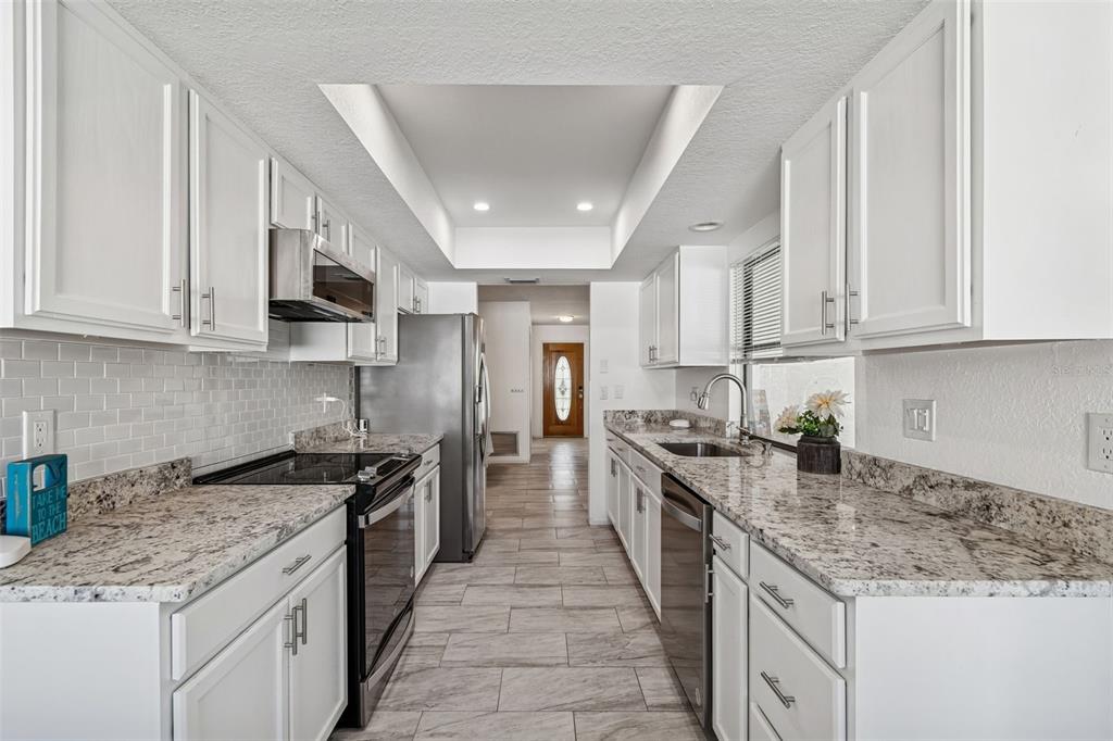 14301 86th Avenue North Seminole, FL 33776 - Photo 28 of 59 a kitchen with stainless steel appliances granite countertop a stove top oven a sink a counter space and cabinets