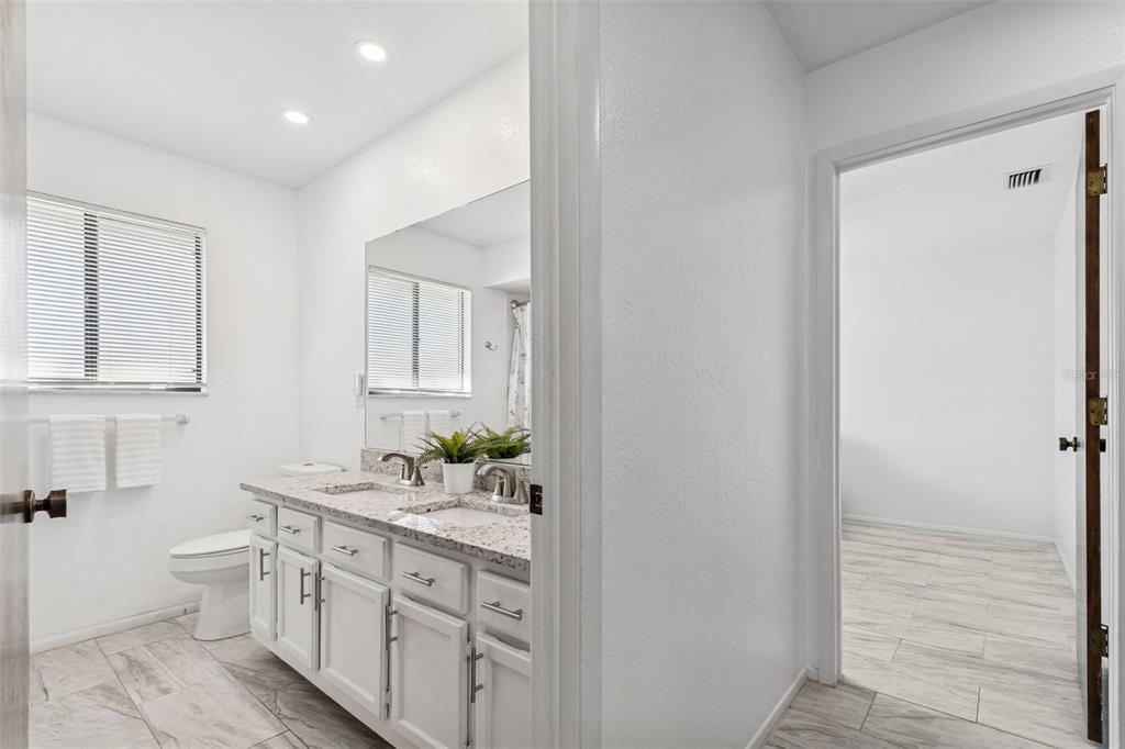 14301 86th Avenue North Seminole, FL 33776 - Photo 42 of 59 a bathroom with a double vanity sink a mirror and a bathtub
