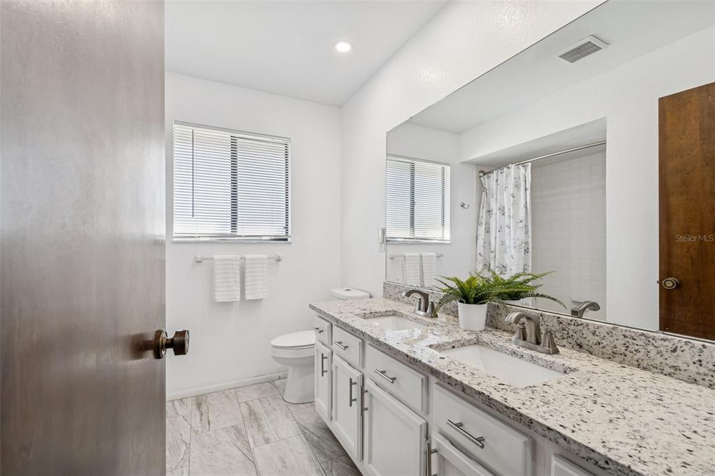 14301 86th Avenue North Seminole, FL 33776 - Photo 43 of 59 a bathroom with a granite countertop sink a toilet and mirror