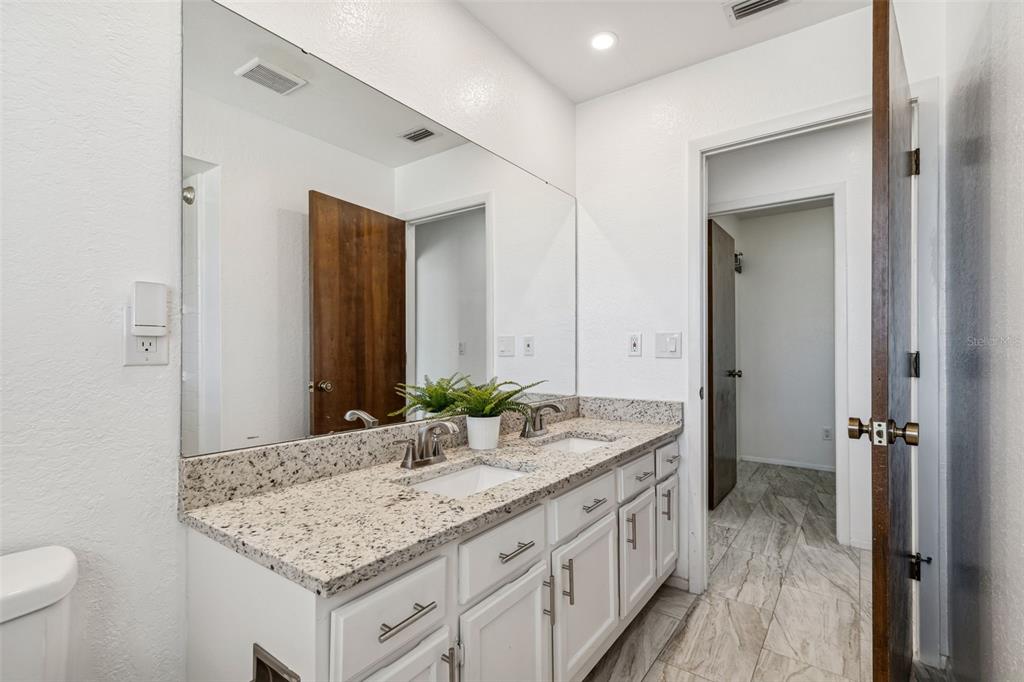 14301 86th Avenue North Seminole, FL 33776 - Photo 45 of 59 a bathroom with a granite countertop sink and a mirror