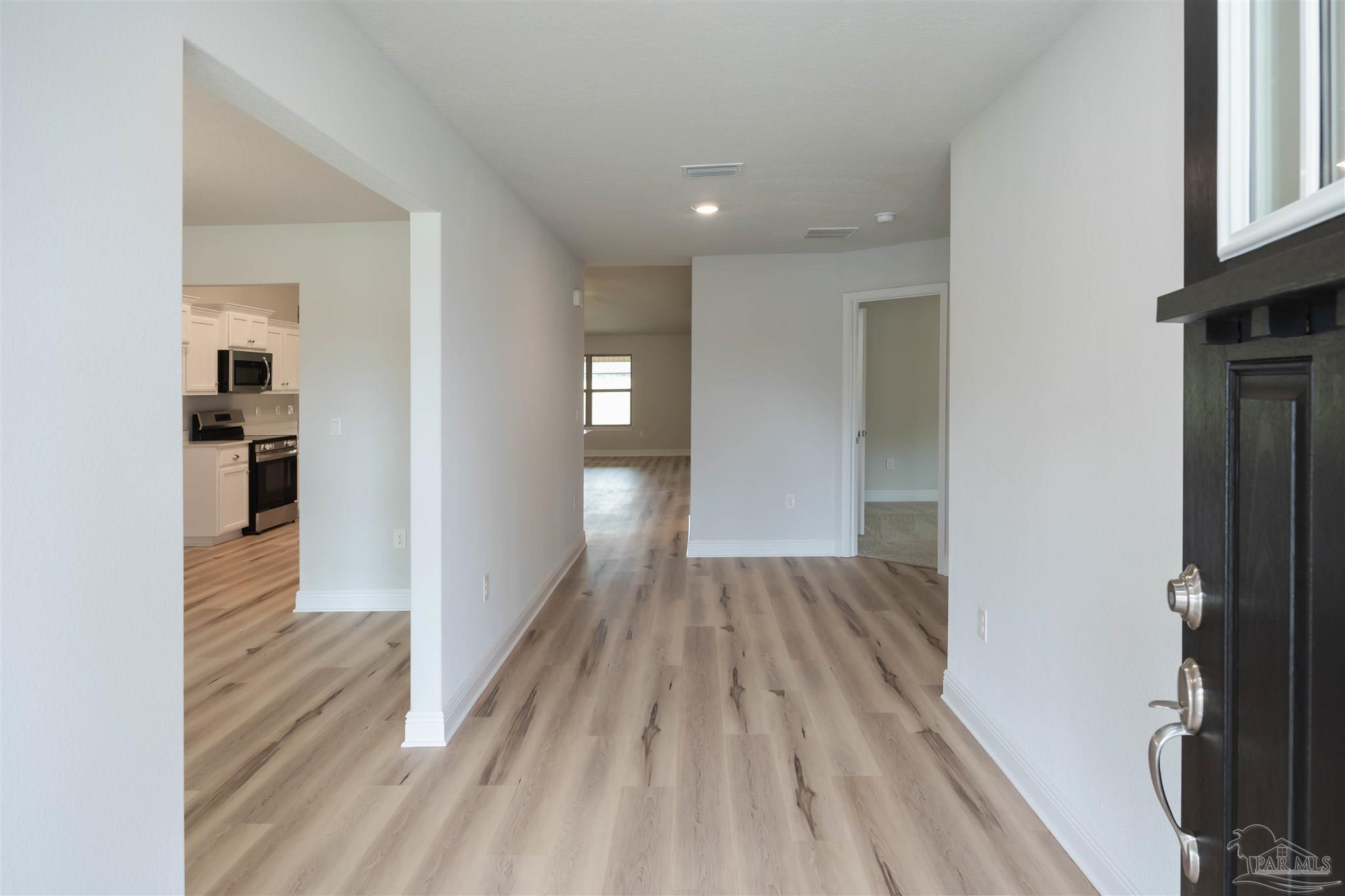 6288 Pineapple Drive Milton, FL 32570 - Photo 5 of 32 a view of a hallway with wooden floor and a living room