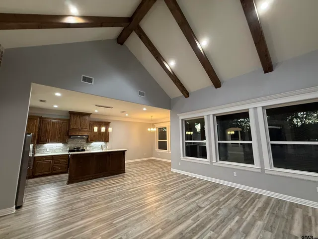 a view of a big room with wooden floor and kitchen