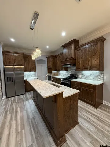 a kitchen with stainless steel appliances kitchen island granite countertop a stove a refrigerator and a sink