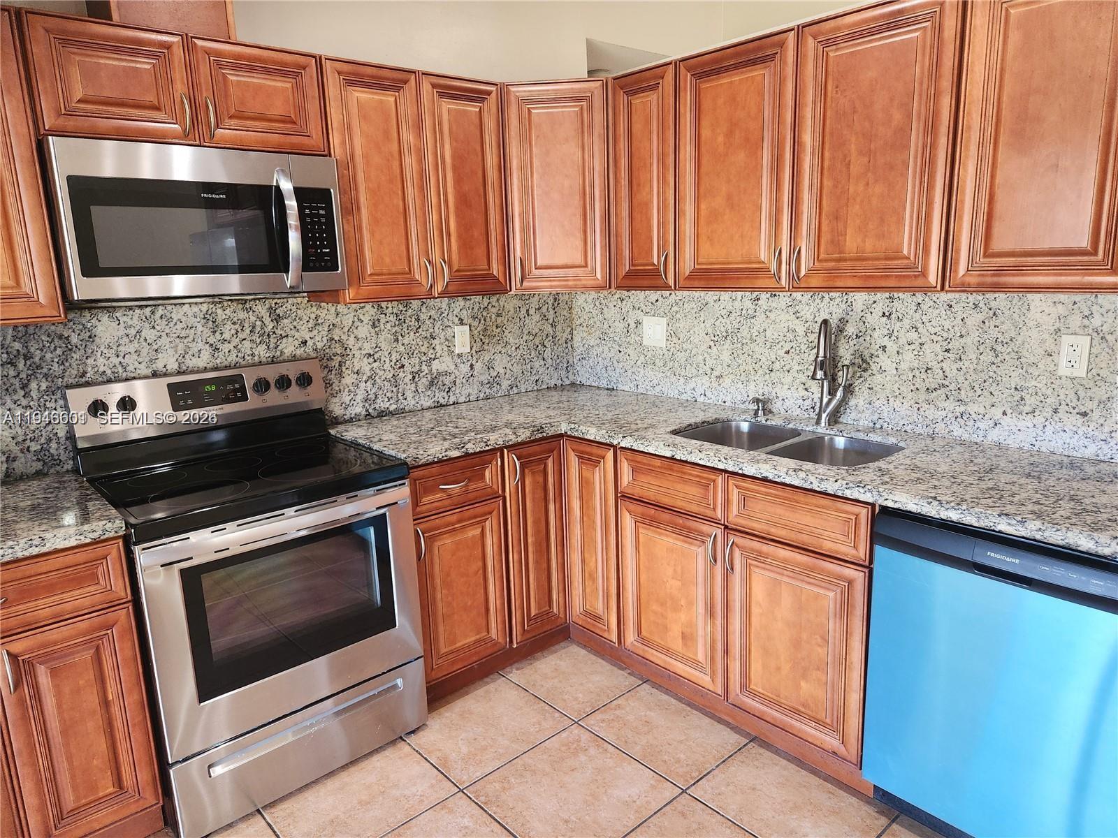 18303 Southwest 139th Place Miami, FL 33177 - Photo 6 of 19 a kitchen with granite countertop stainless steel appliances a stove microwave and sink