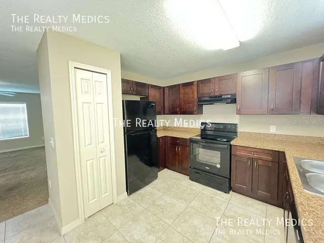 a kitchen with granite countertop a refrigerator and a stove top oven