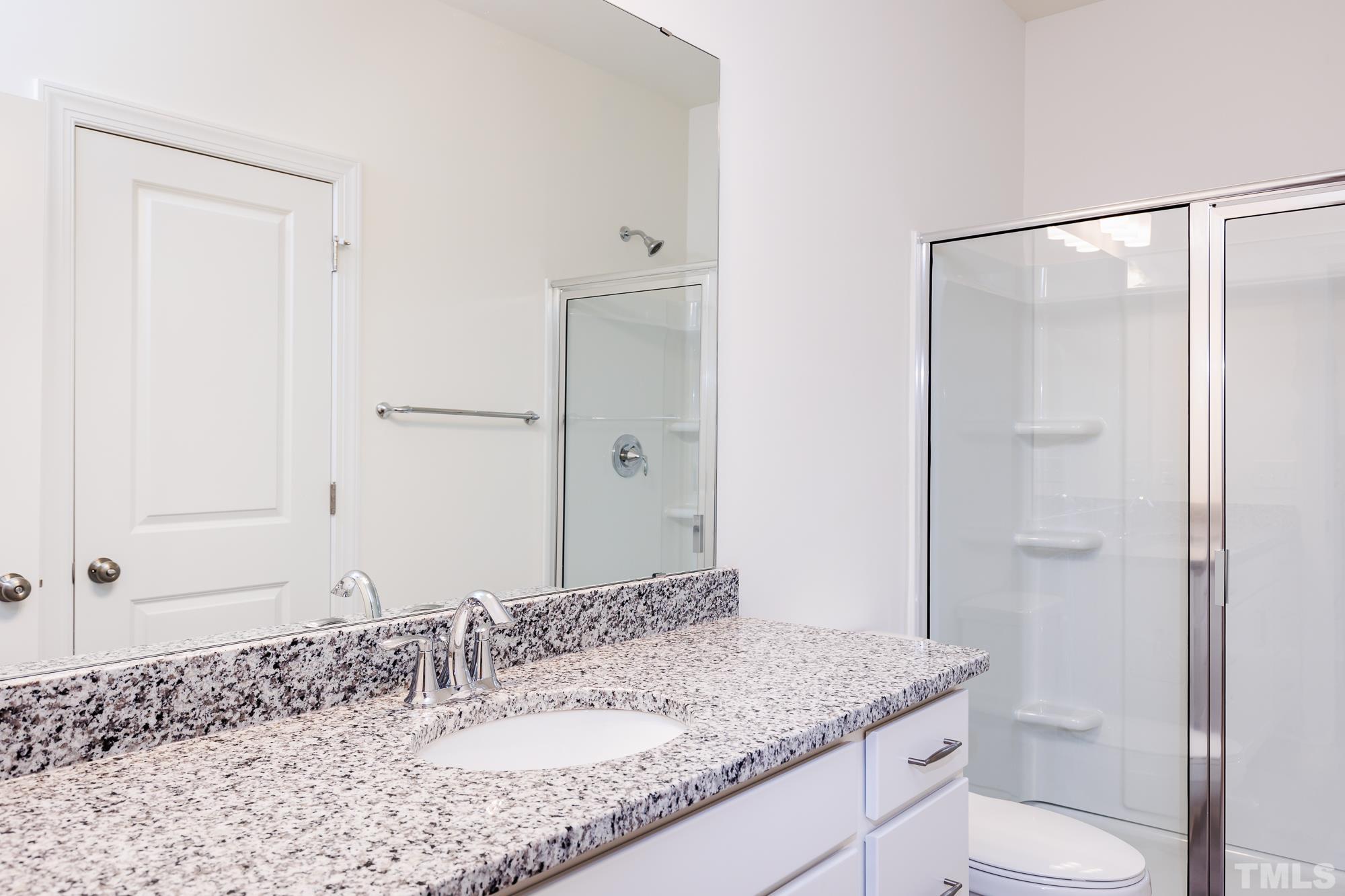 6928 Leesville Road, Unit 5 Raleigh, NC 27613 - Photo 16 of 16 a bathroom with a granite countertop sink a toilet and shower