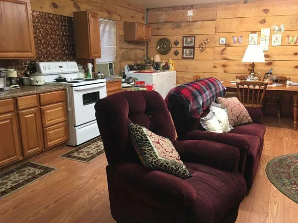a living room with stainless steel appliances furniture a rug and a kitchen
