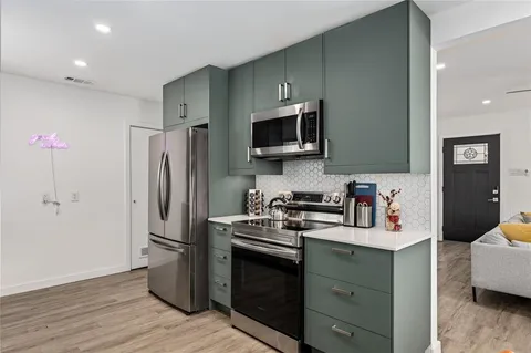 a kitchen with stainless steel appliances a dining table chairs wooden floors and wooden cabinets