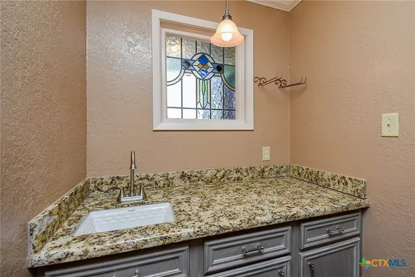 a kitchen with granite countertop a refrigerator a stove a sink and a dining table with wooden floor