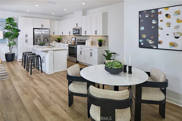 a kitchen with stainless steel appliances kitchen island a table chairs and a refrigerator