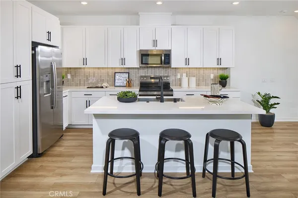 a kitchen with stainless steel appliances granite countertop a table chairs stove a refrigerator and microwave
