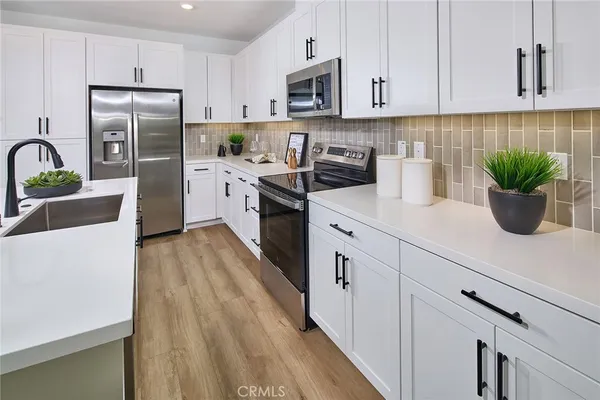 a kitchen with stainless steel appliances white cabinets and wooden floor