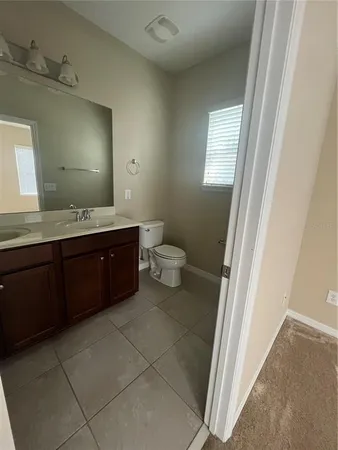 a spacious bathroom with a granite countertop sink a toilet and a mirror