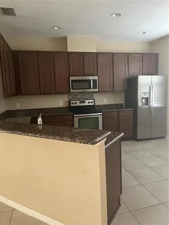 a kitchen with stainless steel appliances granite countertop a refrigerator a stove a sink and a microwave