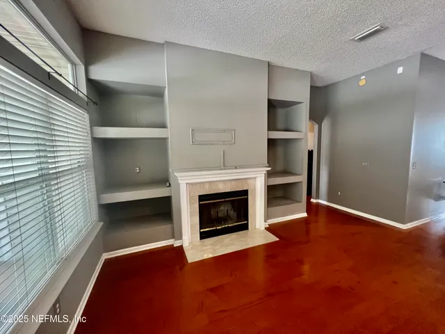 a view of an empty room with a fireplace and a window