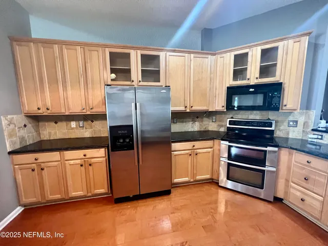 a kitchen with stainless steel appliances granite countertop a stove a sink and a refrigerator
