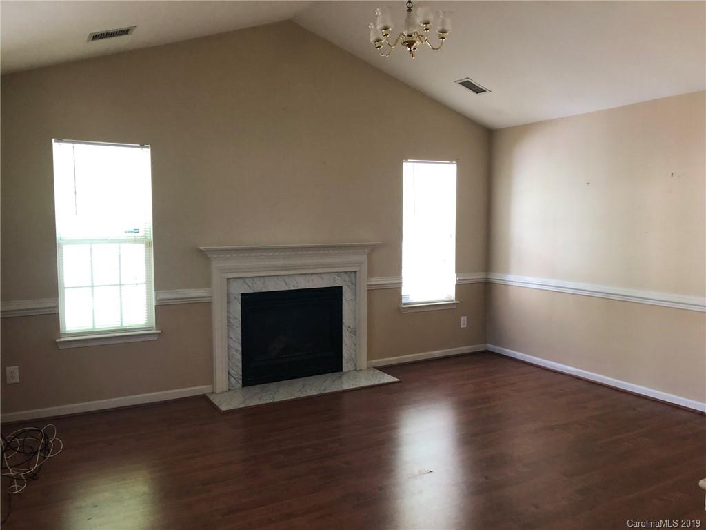 6319 Nevin Road Charlotte, NC 28262 - Photo 3 of 7 an empty room with wooden floor fireplace and windows