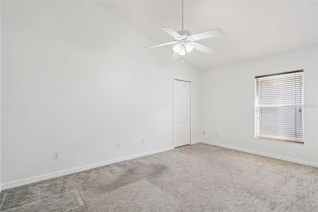 an empty room with windows and fan