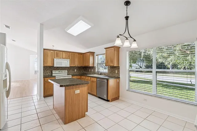 a kitchen with stainless steel appliances granite countertop a stove a sink dishwasher and a refrigerator