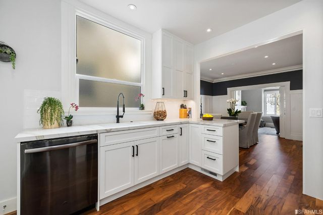 a kitchen with white cabinets and sink