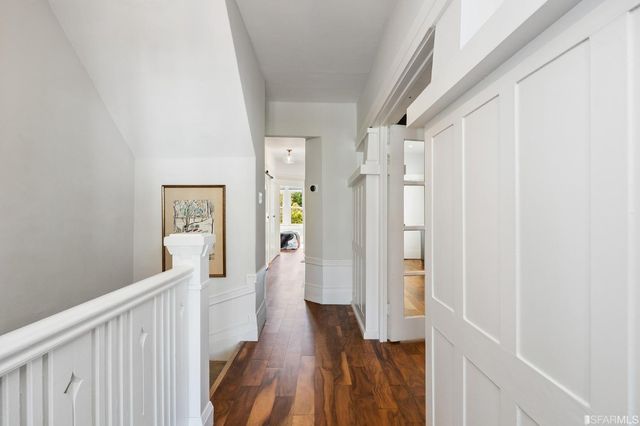 a view of a hallway with wooden floor and staircase