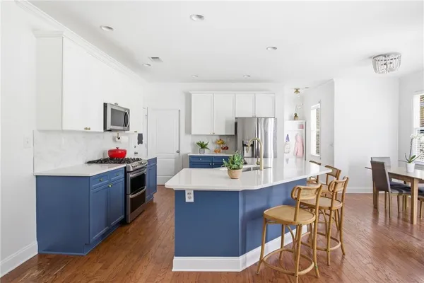 a kitchen with stainless steel appliances a dining table chairs and wooden cabinets