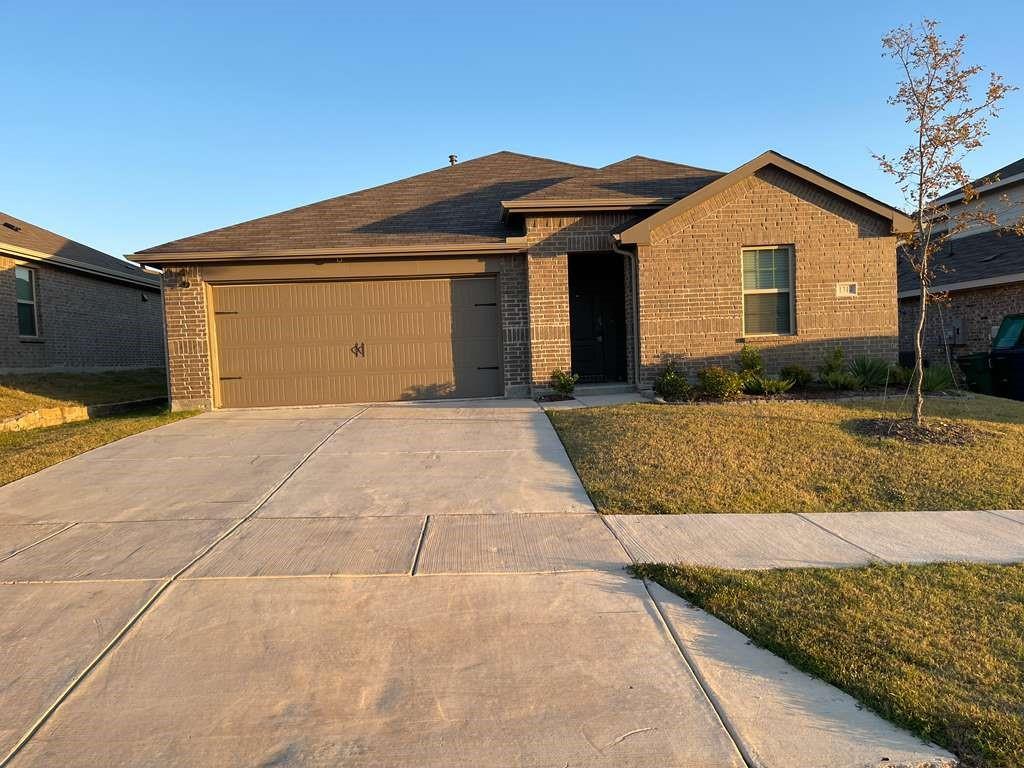 View of front of property featuring brick siding, driveway, a garage, and a front lawn