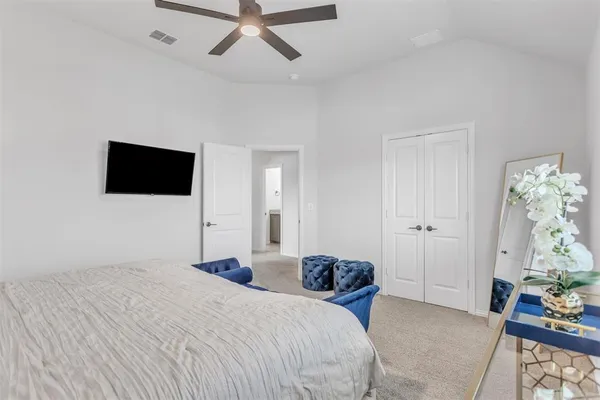 a bedroom with a bed and a flat tv screen on dresser