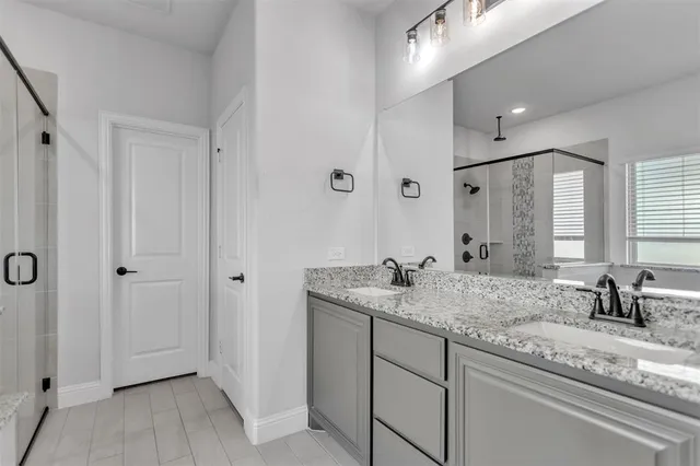 a bathroom with a granite countertop sink a mirror and shower