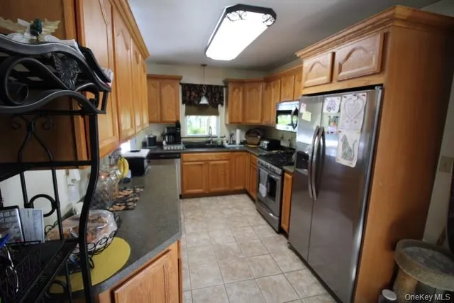 a kitchen with stainless steel appliances granite countertop a refrigerator a stove and a sink with wooden floor