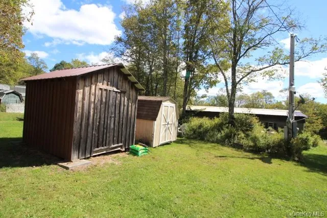 a view of backyard with large trees and wooden fence