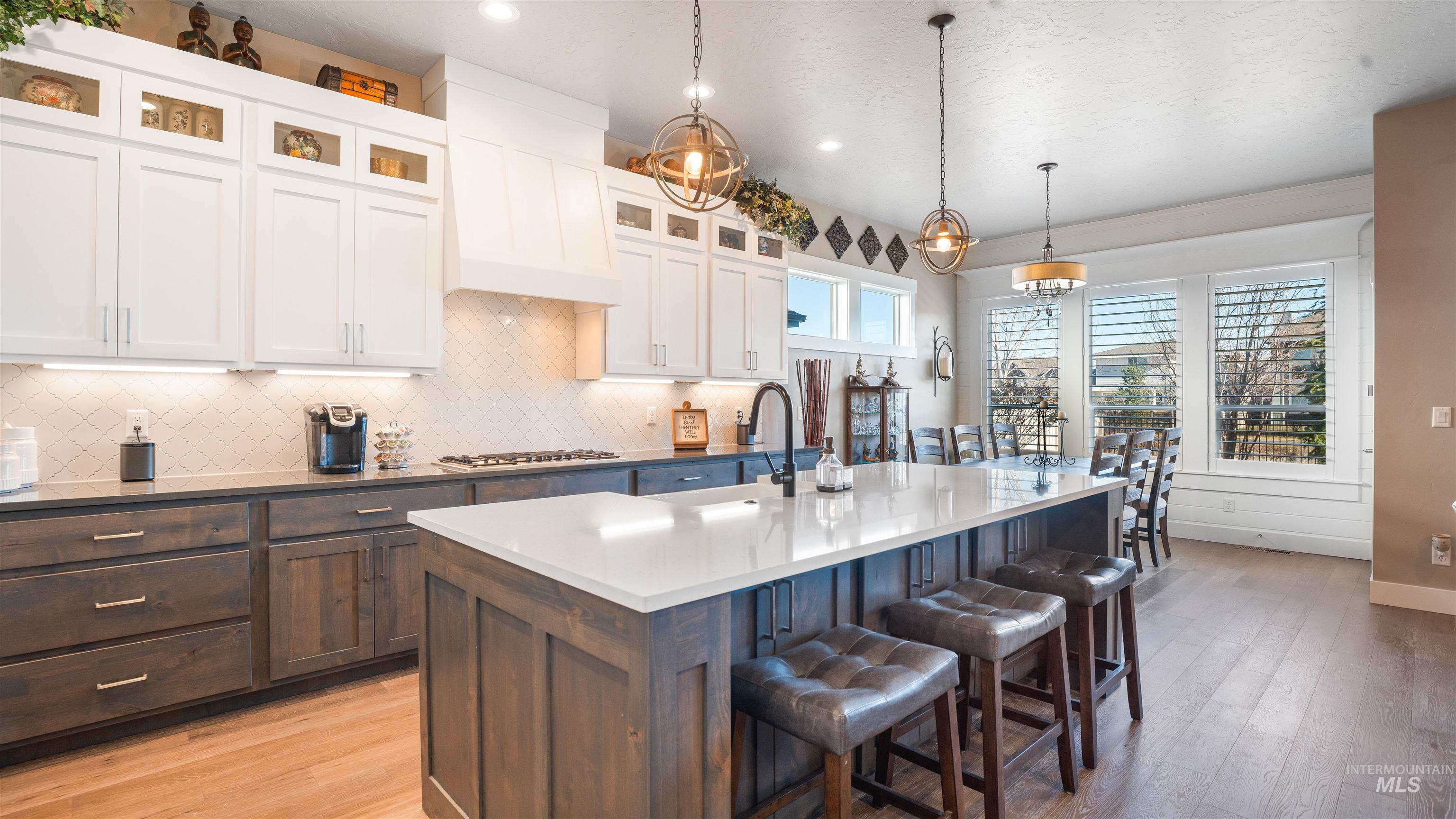 4676 South Abbot Meridian, ID 83642 - Photo 24 of 49 Kitchen with two tone cabinetry, a breakfast bar area, light wood-style flooring, pendant lighting, and glass insert cabinets