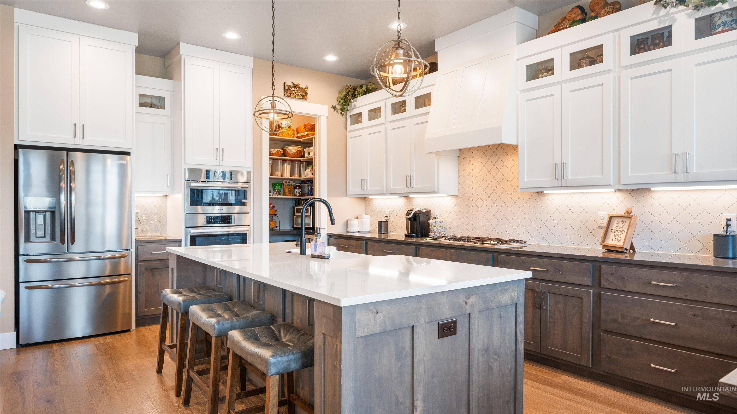 4676 South Abbot Meridian, ID 83642 - Photo 25 of 49 Kitchen with glass insert cabinets, stainless steel appliances, a kitchen bar, two tone color scheme, and an island with sink