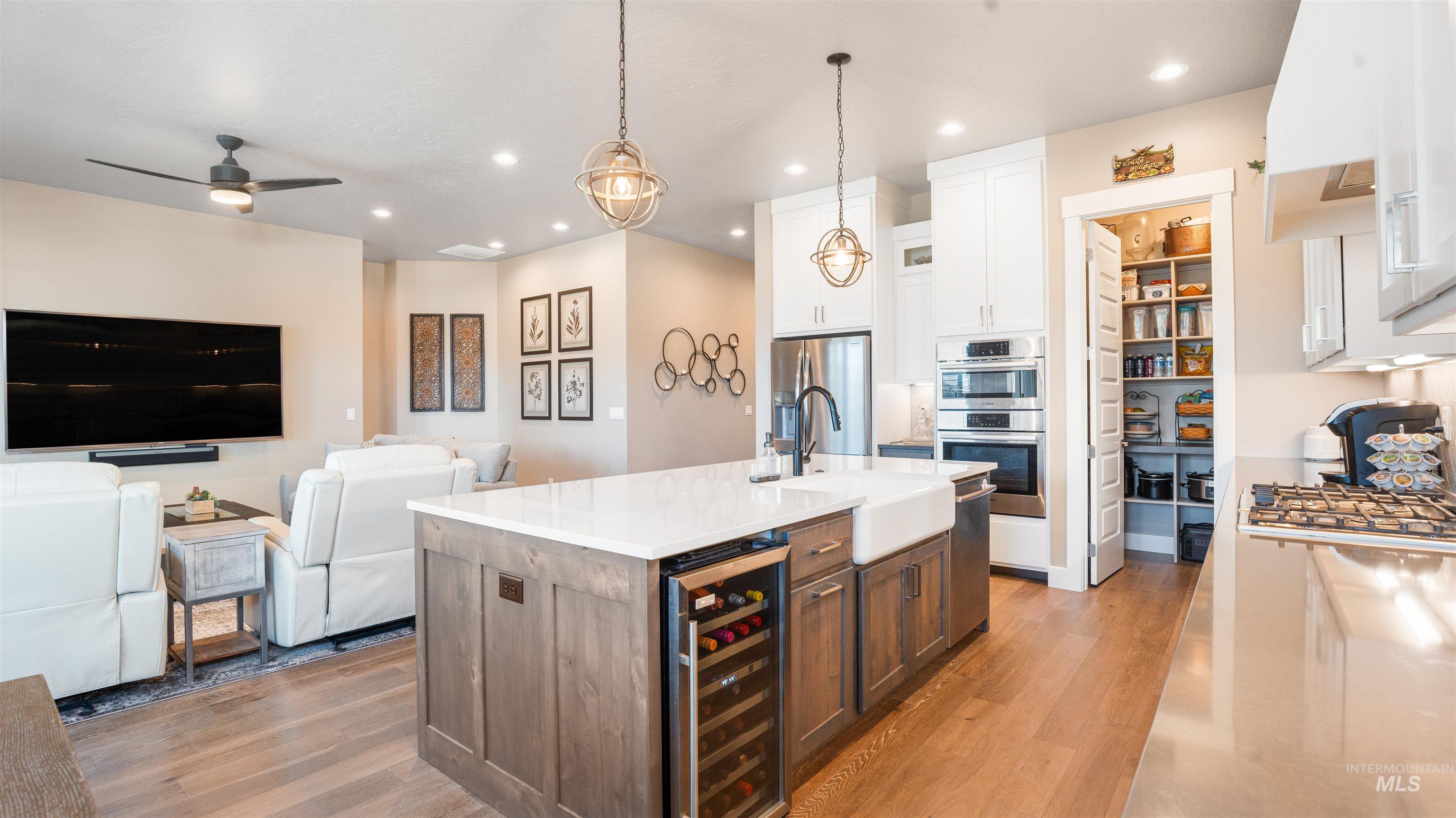 4676 South Abbot Meridian, ID 83642 - Photo 48 of 49 Two tone kitchen with open floor plan, two tone color scheme, a center island with sink, beverage cooler, and pendant lighting