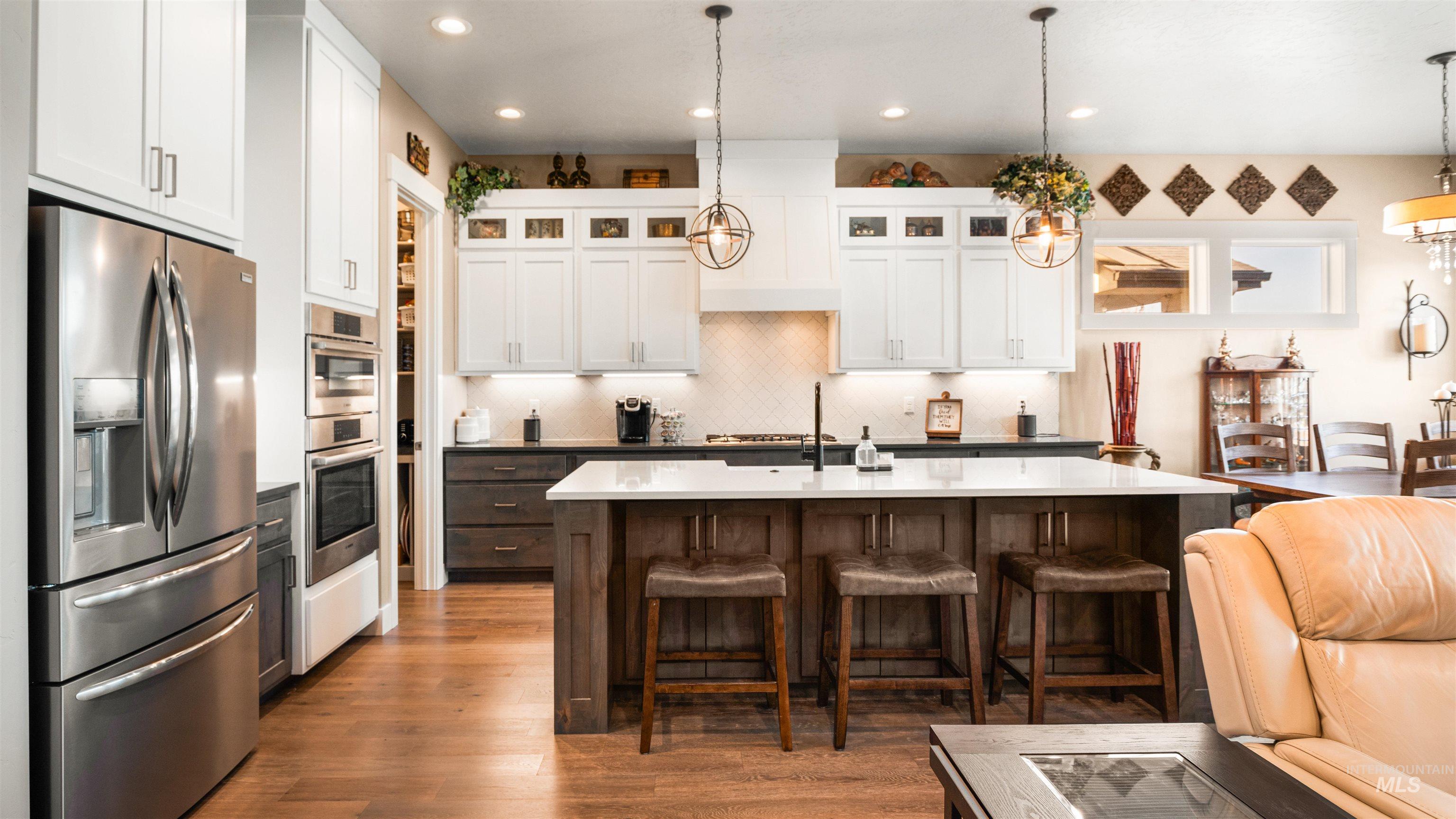 4676 South Abbot Meridian, ID 83642 - Photo 27 of 49 Two tone kitchen with dual tone cabinetry, stainless steel appliances, a breakfast bar area, dark wood finished floors, and a center island with sink