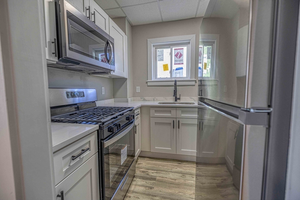 66 Lyon Street, Unit 1 Fall River, MA 02721 - Photo 3 of 11 a kitchen with stainless steel appliances granite countertop a stove top oven a sink and dishwasher