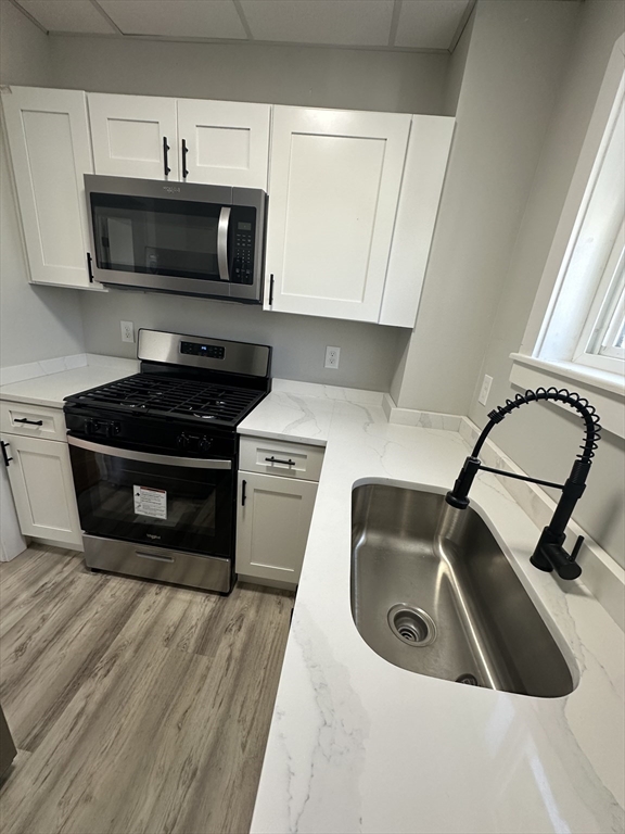 66 Lyon Street, Unit 1 Fall River, MA 02721 - Photo 4 of 11 a kitchen with a sink a stove and cabinets