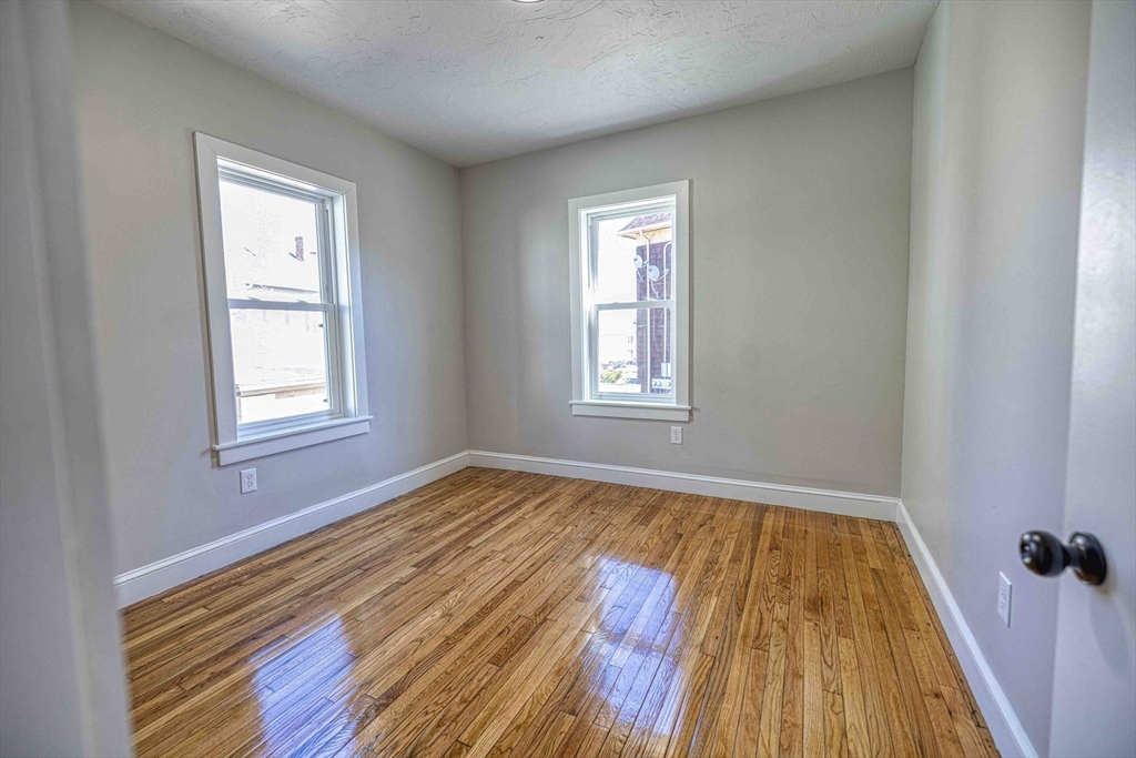 66 Lyon Street, Unit 1 Fall River, MA 02721 - Photo 7 of 11 a view of an empty room with wooden floor and a window