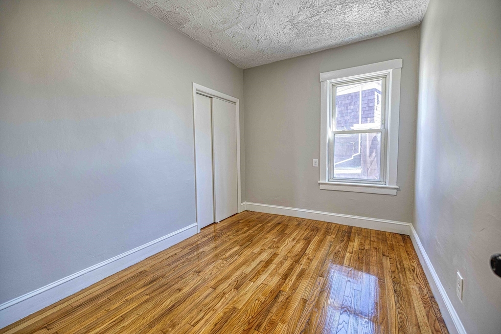66 Lyon Street, Unit 1 Fall River, MA 02721 - Photo 9 of 11 an empty room with wooden floor and windows