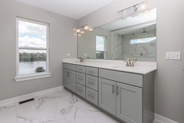 a bathroom with double sink a mirror a window and vanity