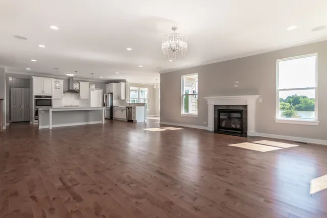 a view of a livingroom with a fireplace wooden floor and windows
