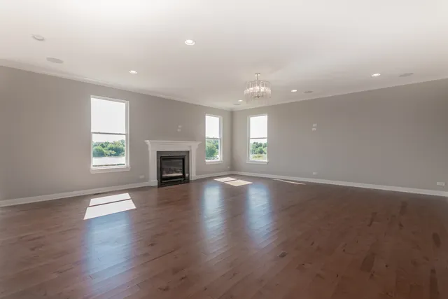 an empty room with wooden floor fireplace and windows