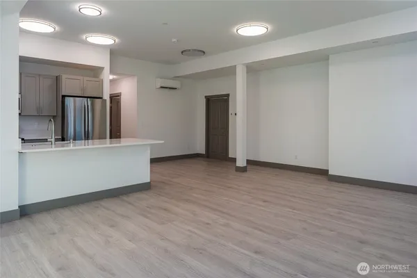 a view of a kitchen with refrigerator and wooden floor