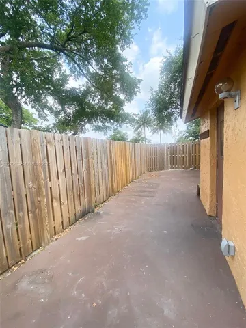 a view of a backyard with wooden fence and large trees