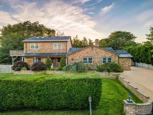 a view of a house with a big yard plants and large trees